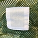 Closeup of White ID Tag Sewn on Center of Army Green Mesh Laundry Bag