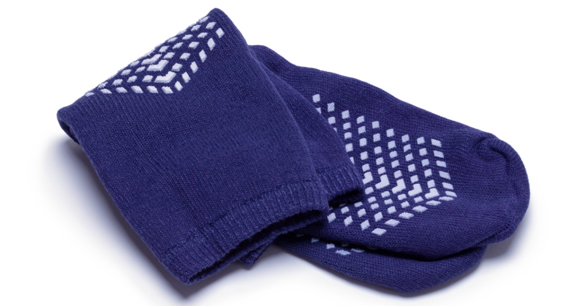 A pair of blue grip socks with white tread dots folded on a plain white background, showing ribbed fabric texture.
